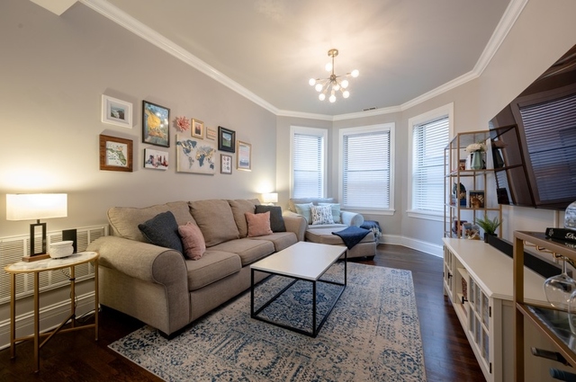 665 West Barry Avenue, Unit 2S Chicago, IL 60657 - Photo 2 of 10 a living room with furniture a chandelier and a flat screen tv