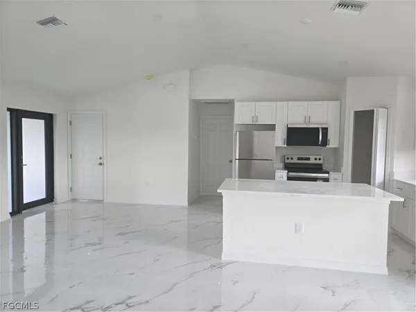 a view of kitchen with stainless steel appliances cabinets and empty shelves