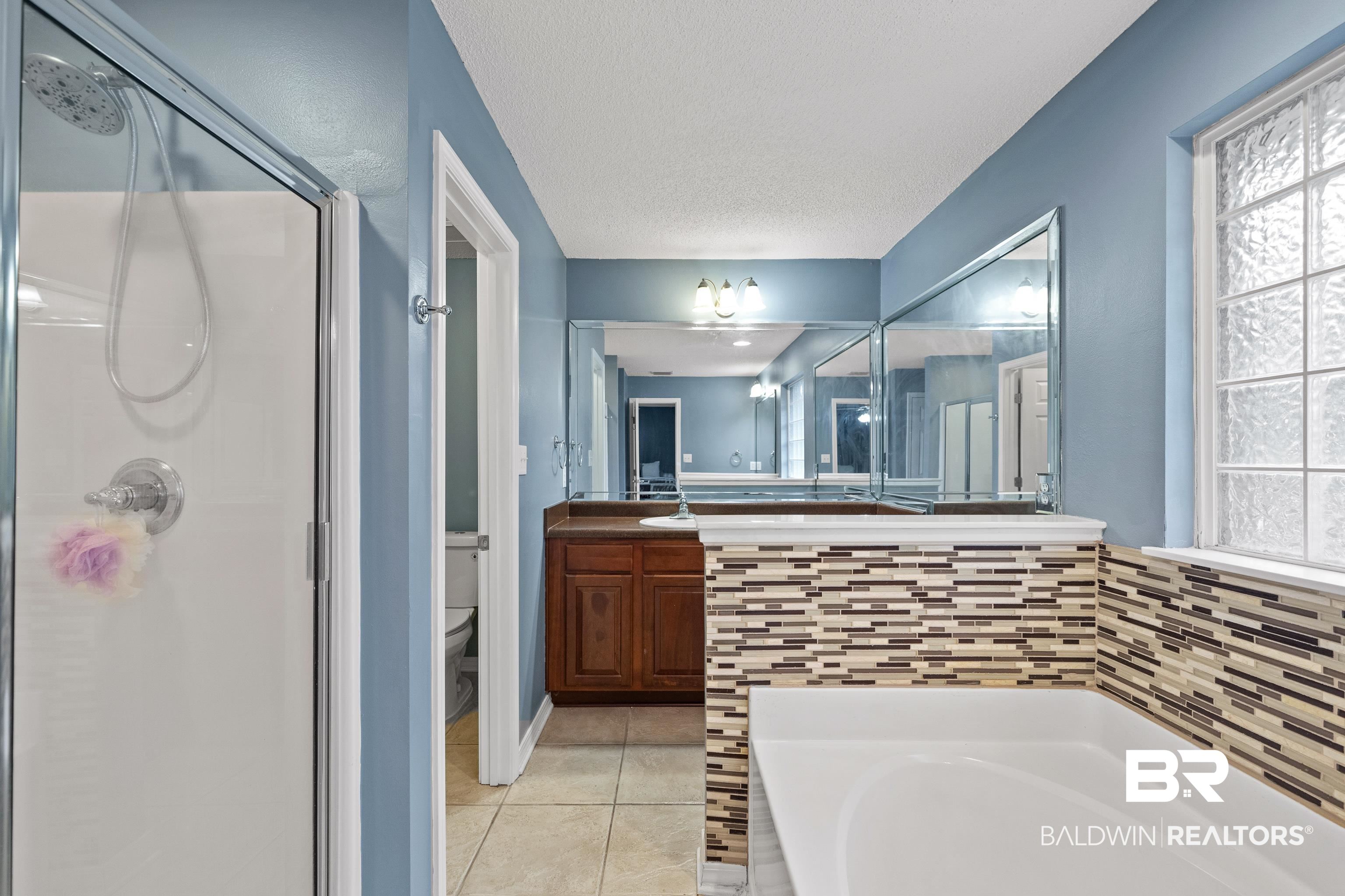 9552 Collier Loop Daphne, AL 36526 - Photo 18 of 28 Bathroom with a shower stall, toilet, a garden tub, 2 vanity areas, and tile patterned flooring