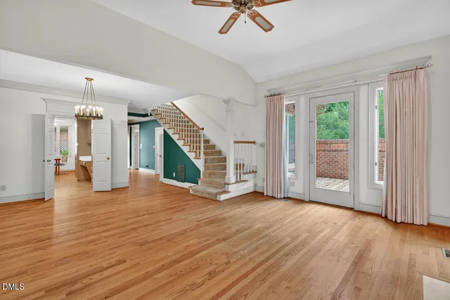 a view of an empty room with wooden floor fireplace and a window