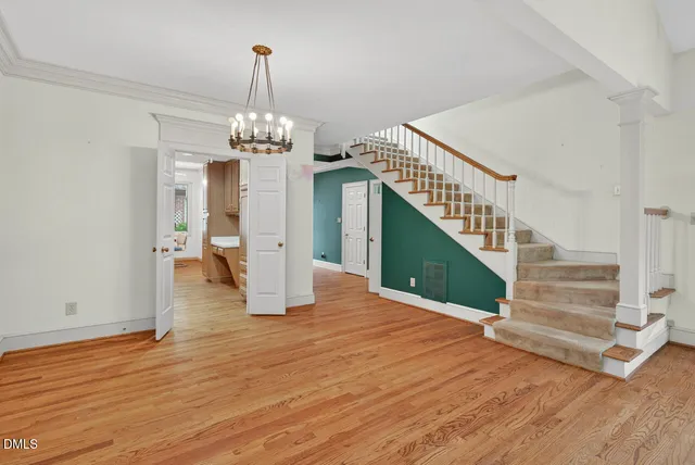 an empty room with stairs and wooden floor chandelier