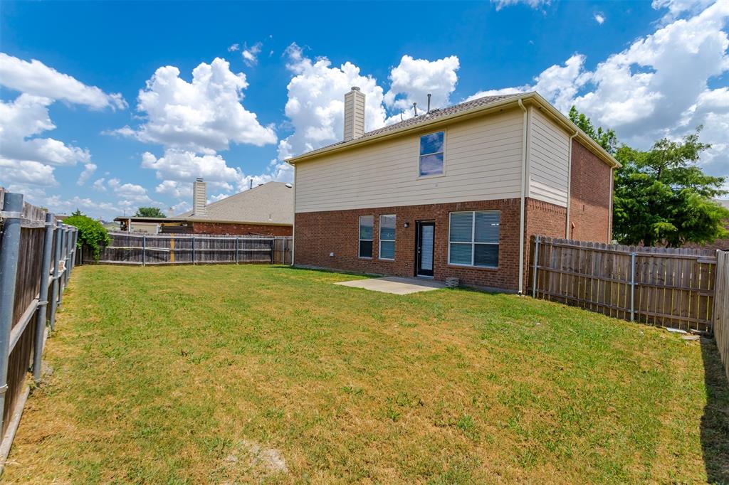 203 Arabian Road Waxahachie, TX 75165 - Photo 23 of 24 Expansive backyard featuring a privacy fence, a brick and siding exterior, multiple windows, and a patio door