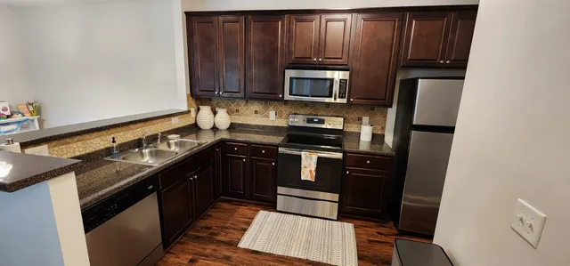 a kitchen with granite countertop a refrigerator stove and microwave