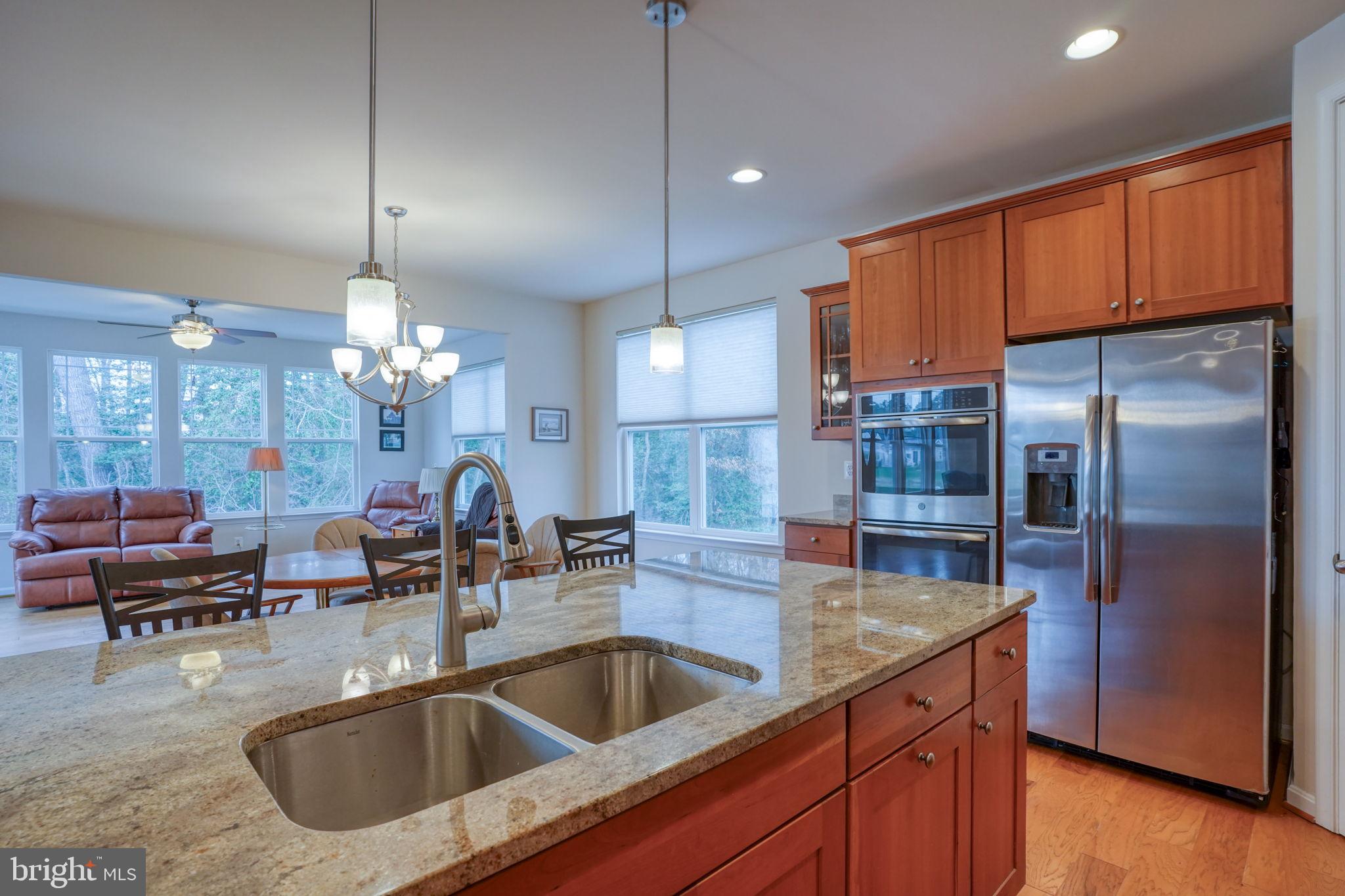 34273 Spring Brook Avenue Lewes, DE 19958 - Photo 13 of 73 a kitchen with stainless steel appliances granite countertop a sink a refrigerator a stove a dining table and chairs with wooden floor