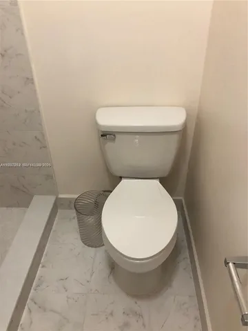 a white toilet sitting next to a white wall