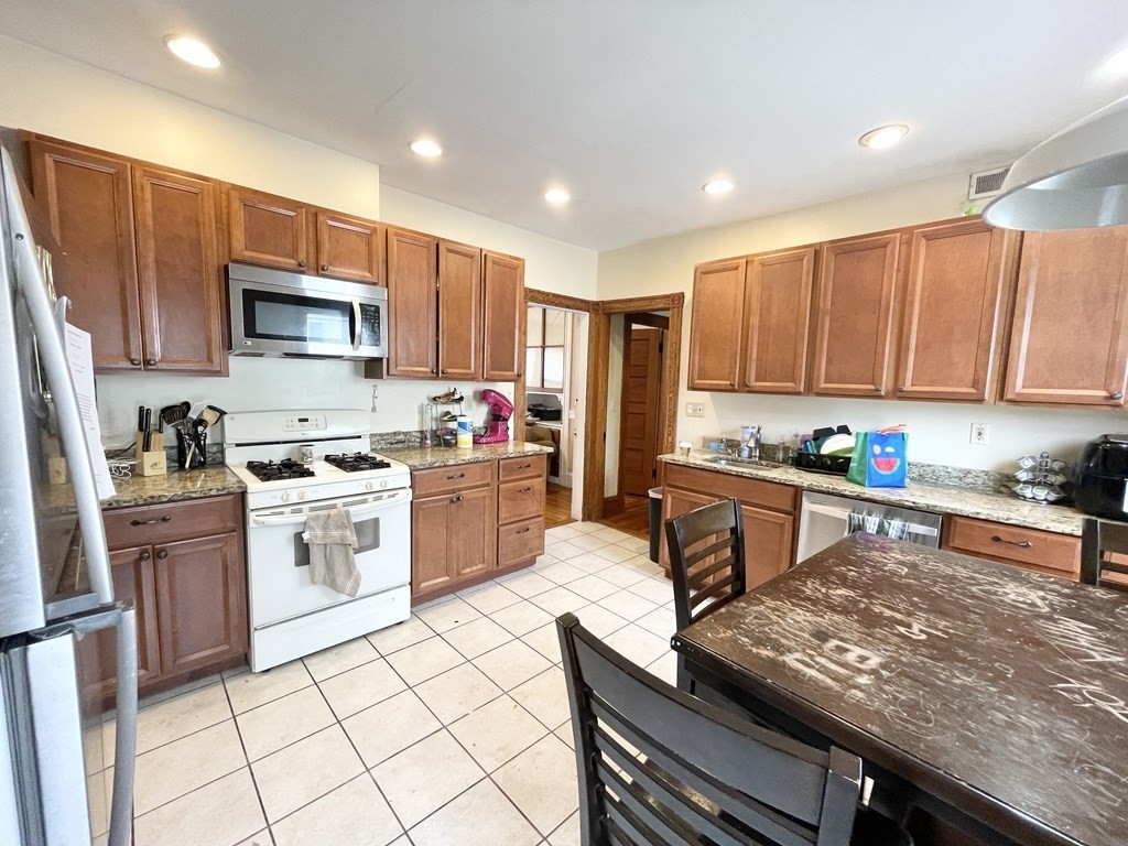 a kitchen with granite countertop a stove top oven a sink dishwasher and a refrigerator with wooden cabinets