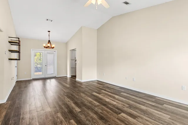 a view of a room with wooden floor a ceiling fan and window