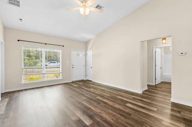 a view of an empty room with wooden floor and a window