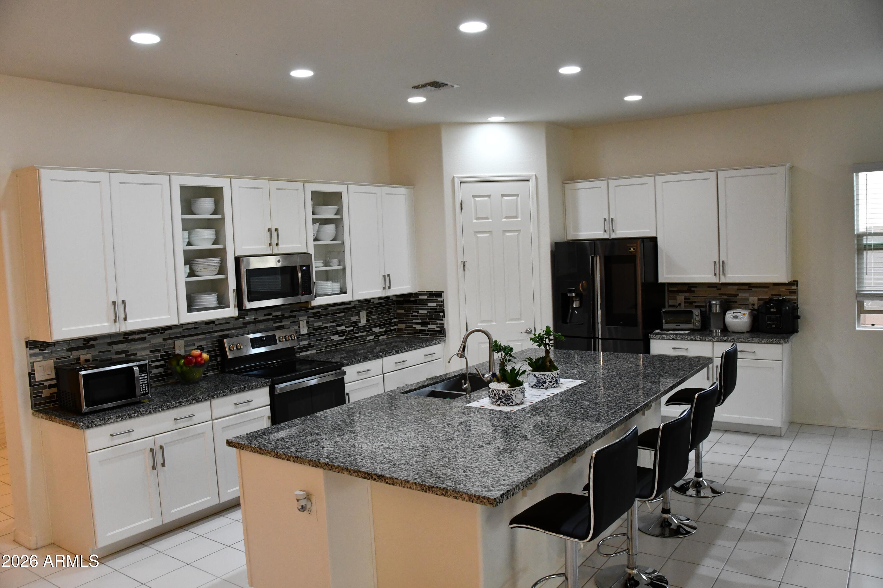 22419 97th Lane Peoria, AZ 85383 - Photo 5 of 22 a kitchen with kitchen island granite countertop a sink and white cabinets