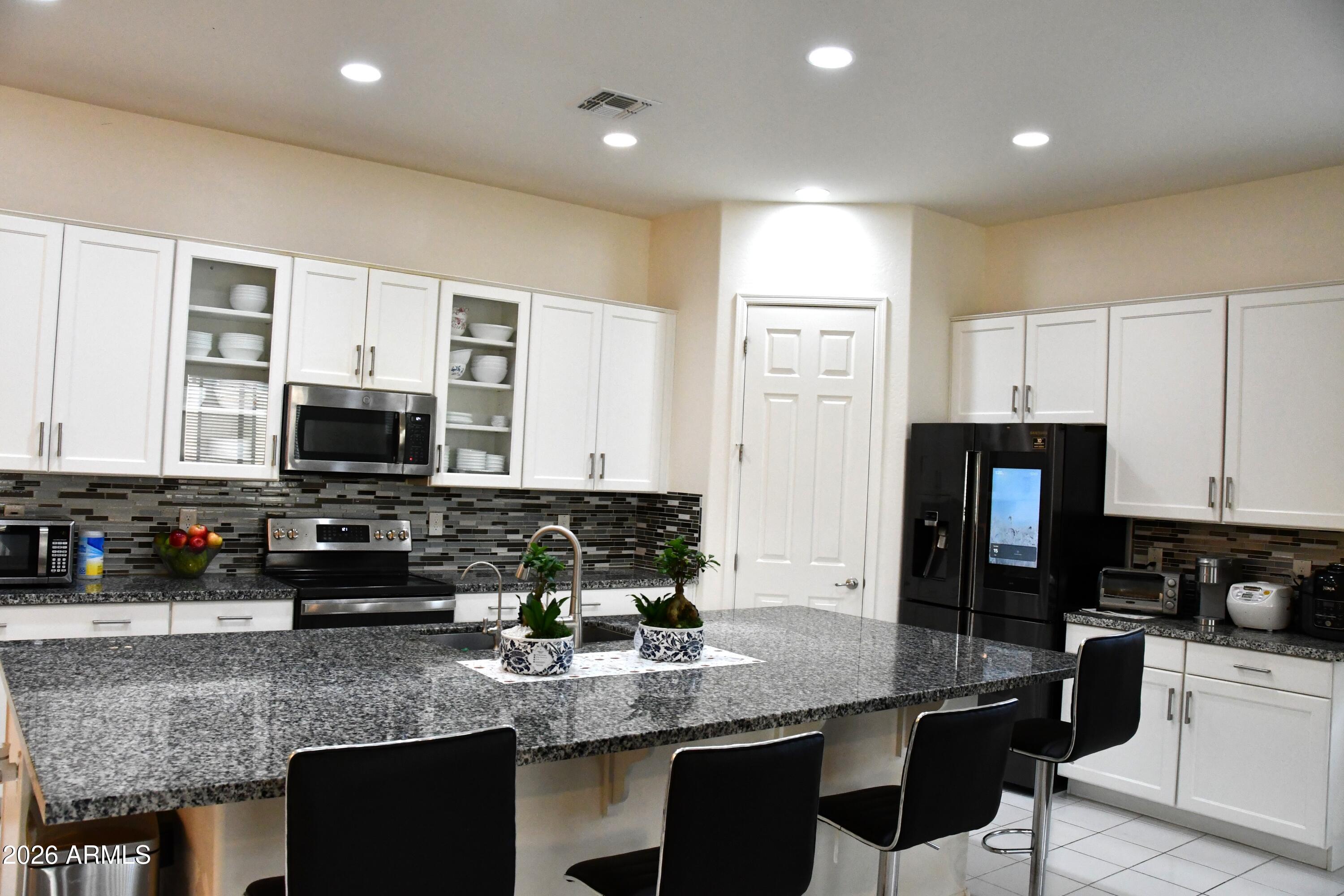 22419 97th Lane Peoria, AZ 85383 - Photo 8 of 22 a kitchen with stainless steel appliances granite countertop a stove a sink a microwave a refrigerator and white cabinets