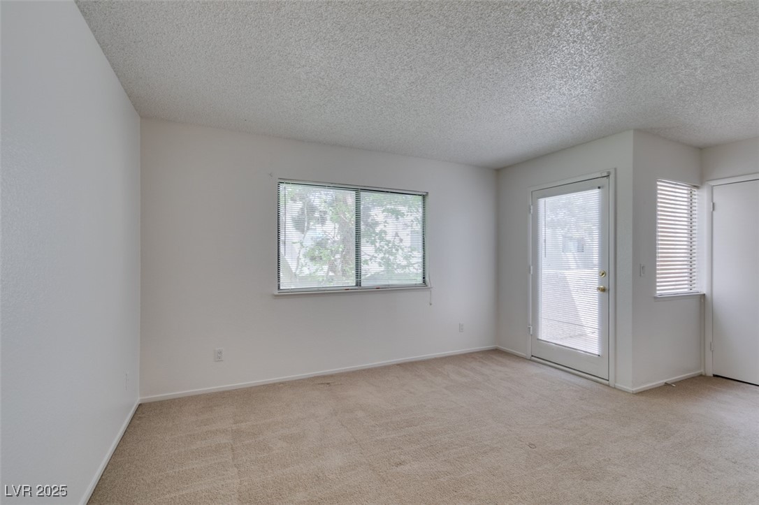 2681 Ruthe Duarte Avenue Las Vegas, NV 89121 - Photo 30 of 43 Carpeted spare room with a textured ceiling, baseboards, and a healthy amount of sunlight