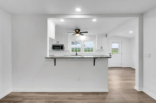 a view of an empty room with wooden floor and a ceiling fan