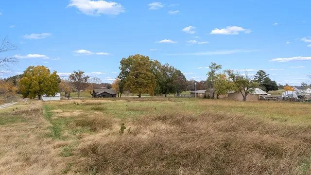 a view of a house with a big yard and large trees