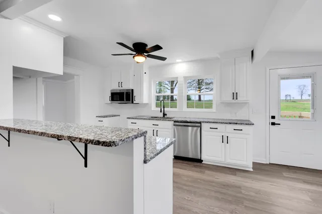 a view of a kitchen with kitchen island a sink stainless steel appliances and cabinets