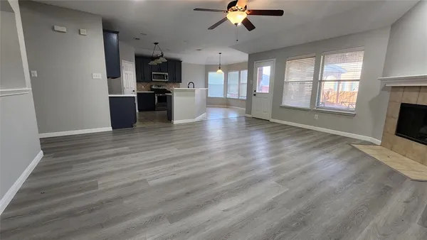 a view of an empty room with a kitchen and a window