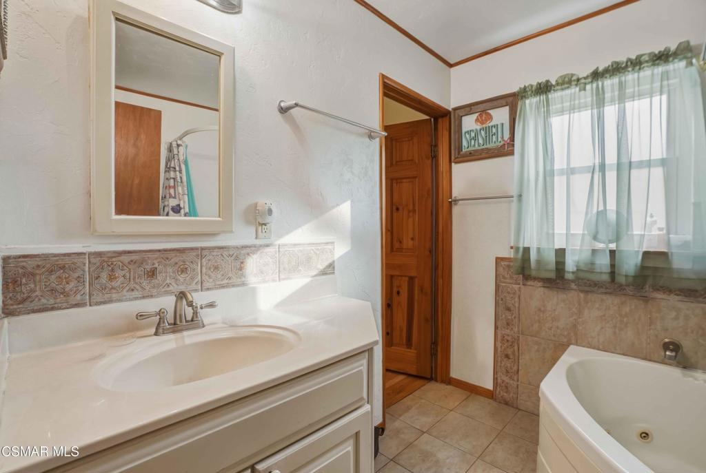 558 East Hemlock Street Oxnard, CA 93033 - Photo 9 of 22 a bathroom with a tub a sink and a large mirror
