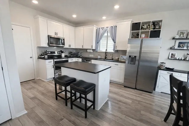 a kitchen with granite countertop a refrigerator a stove a sink a dining table and chairs