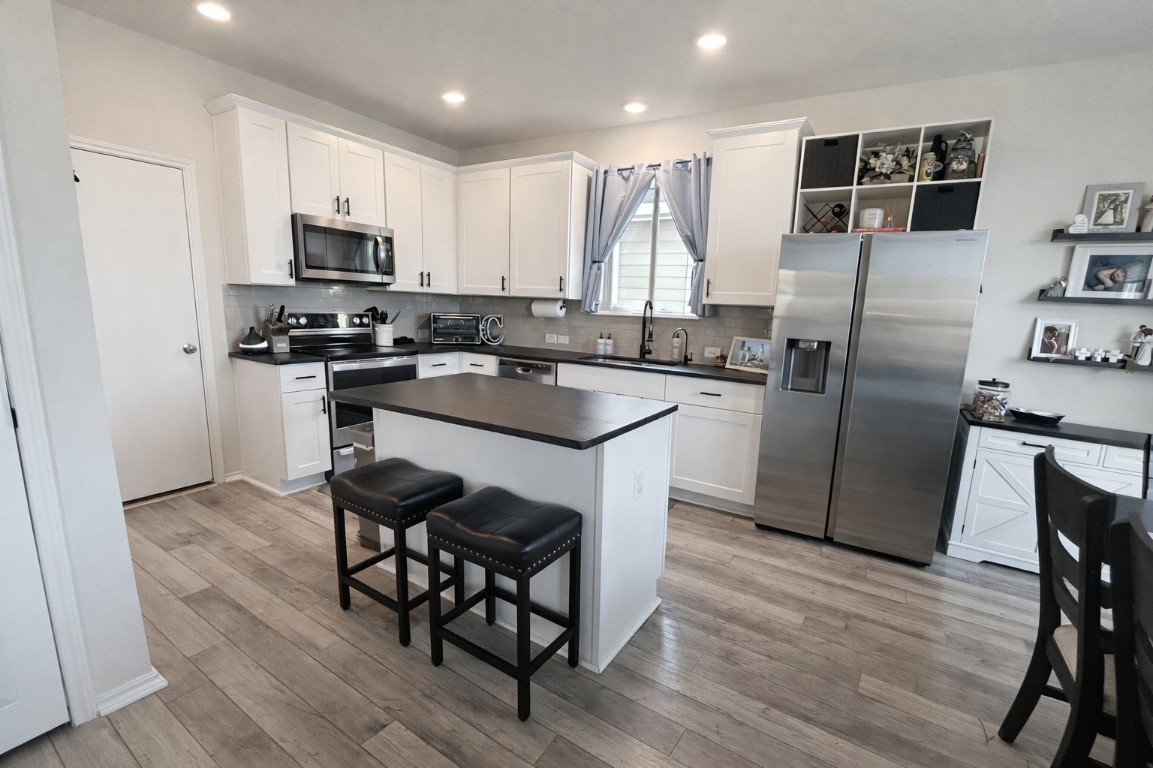 104 Hellfighters Way Jarrell, TX 76537 - Photo 9 of 27 a kitchen with granite countertop a refrigerator a stove a sink a dining table and chairs