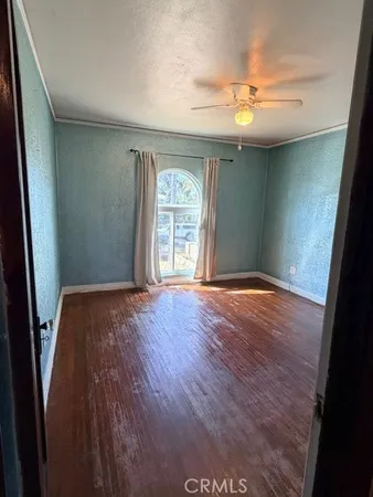 an empty room with wooden floor and chandelier fan