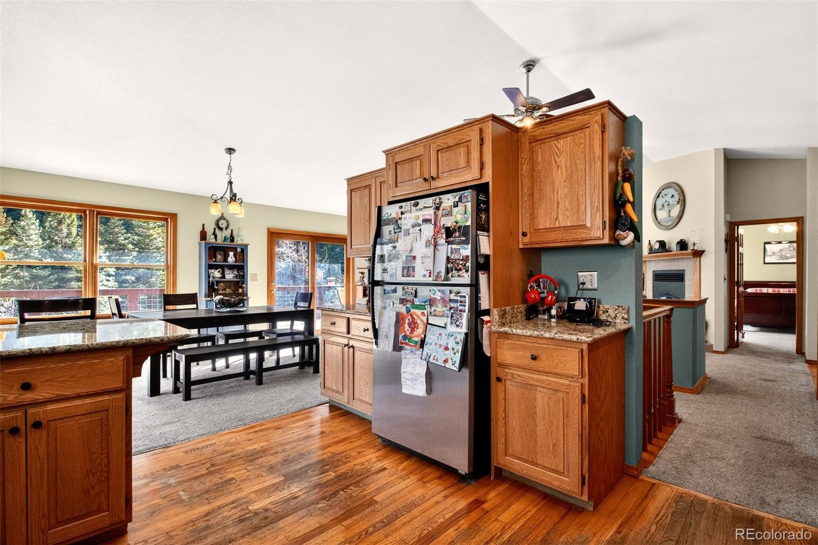 1445 Sutherland Road Manitou Springs, CO 80829 - Photo 14 of 43 a kitchen with stainless steel appliances granite countertop a stove top oven a refrigerator a dining table and chairs with wooden floor