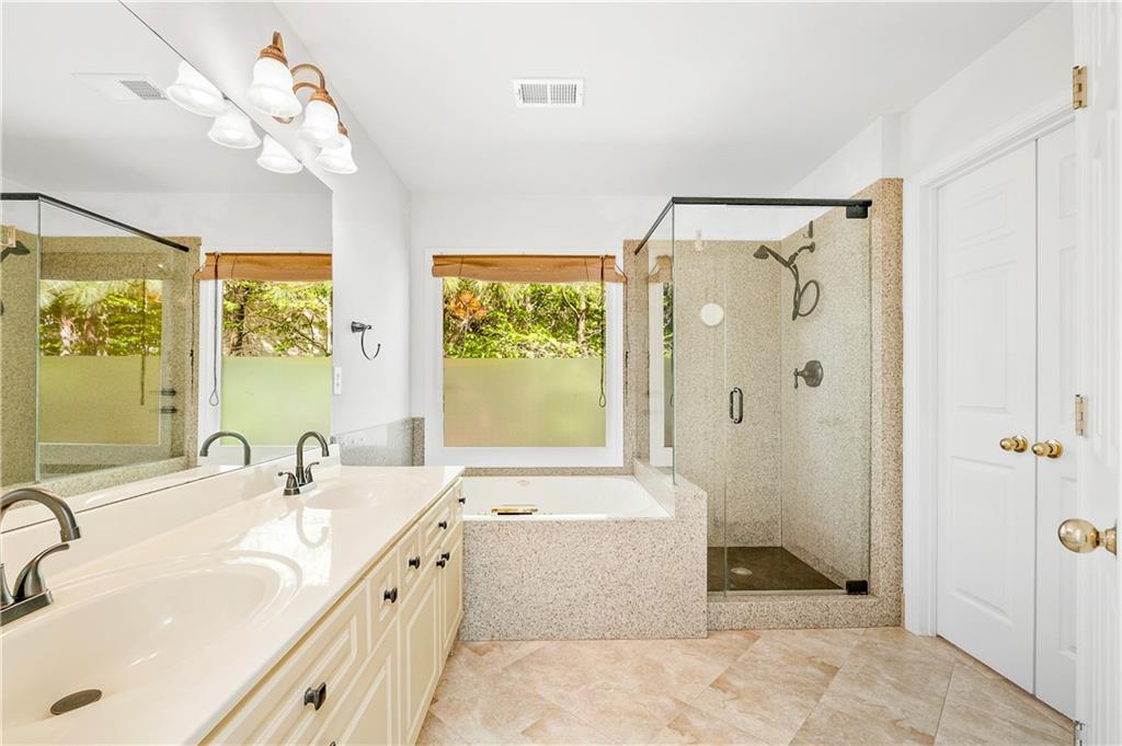 873 Red Rock Court Suwanee, GA 30024 - Photo 25 of 36 a spacious bathroom with a double vanity sink a large mirror and a bathtub
