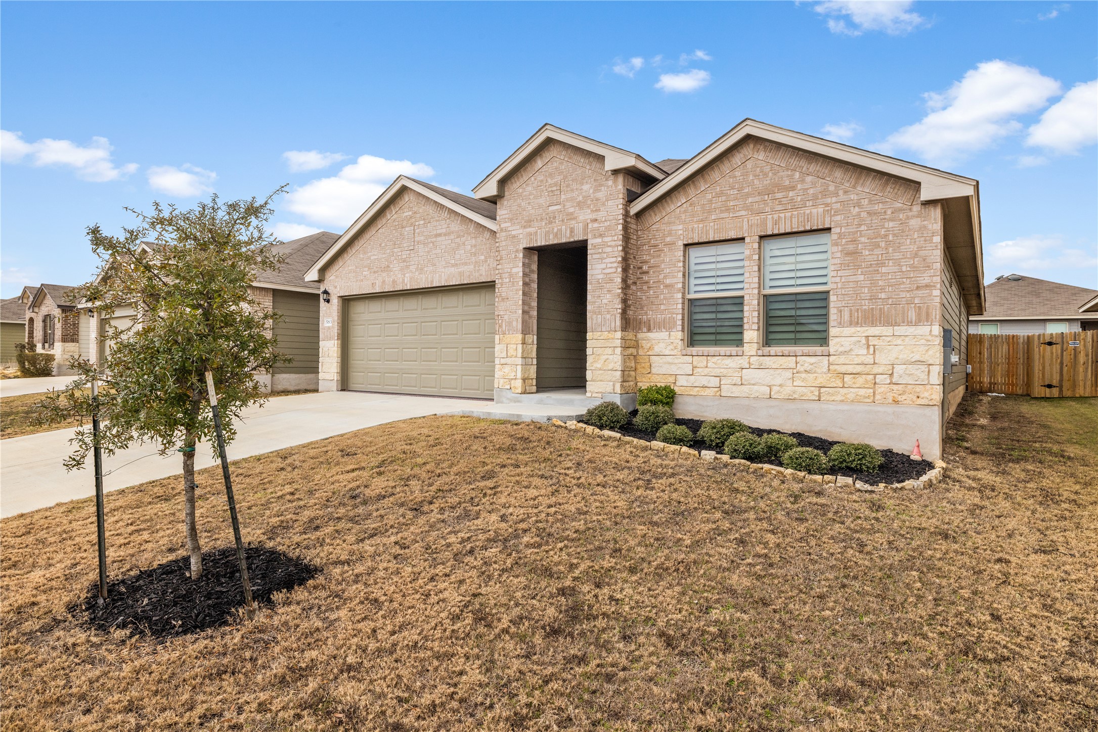 View of front of house with concrete driveway, a garage, brick siding, and stone siding