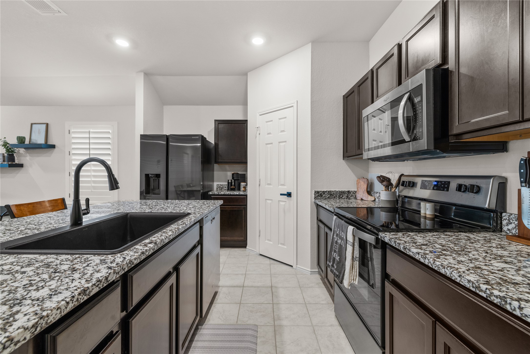 583 Taggart Trail Jarrell, TX 76537 - Photo 10 of 21 Kitchen featuring stainless steel appliances, light stone counters, dark wood finish cabinets, light tile patterned floors, and recessed lighting