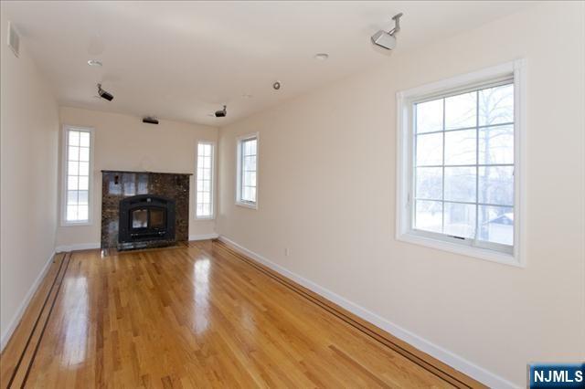 177 Magnolia Avenue Cresskill, NJ 07626 - Photo 4 of 15 an empty room with wooden floor fireplace and windows