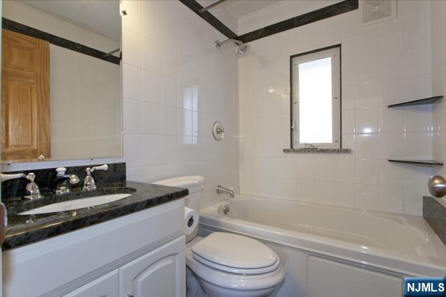 177 Magnolia Avenue Cresskill, NJ 07626 - Photo 7 of 15 a bathroom with a granite countertop sink toilet a mirror and shower