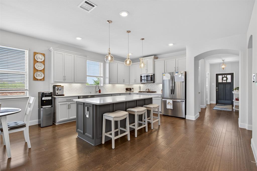 1002 Coppersmith Way Forney, TX 75126 - Photo 2 of 39 a kitchen with stainless steel appliances granite countertop a table chairs refrigerator and sink