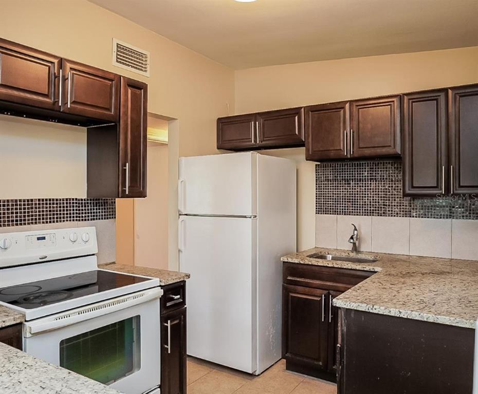 1203 Ferndell Road Orlando, FL 32808 - Photo 3 of 4 a kitchen with granite countertop a refrigerator stove and microwave
