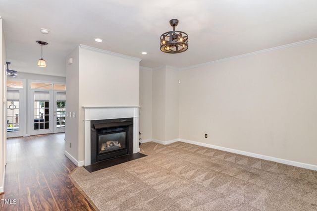 a view of an empty room with wooden floor and a fireplace