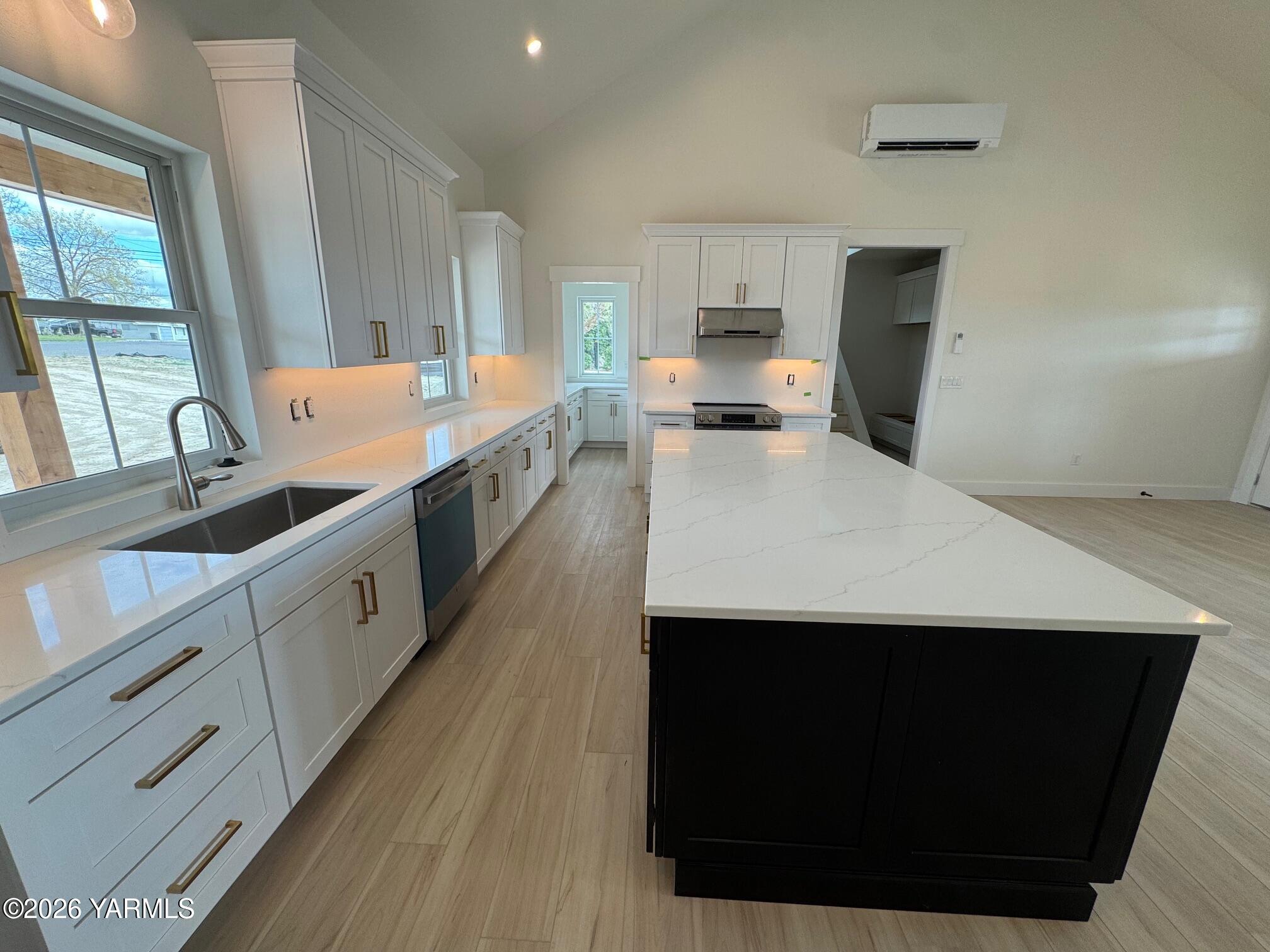304 6th Street Zillah, WA 98953 - Photo 6 of 29 a large white kitchen with kitchen island a sink dishwasher stove with wooden floor and cabinets