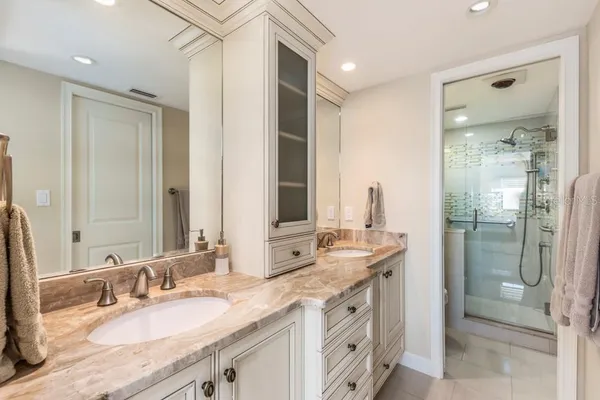 a bathroom with a granite countertop double vanity sink mirror and shower