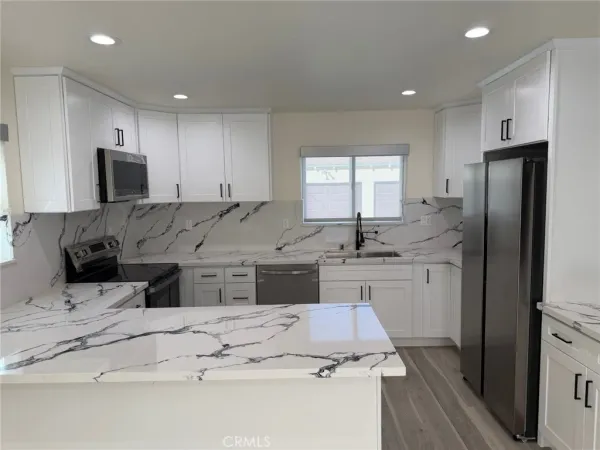 a kitchen with stainless steel appliances granite countertop a sink refrigerator and cabinets