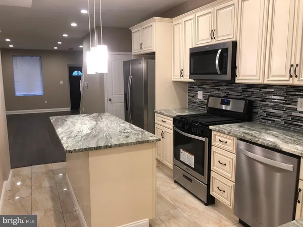 a kitchen with stainless steel appliances granite countertop a refrigerator a stove a sink and a microwave