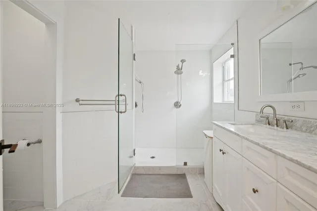 a bathroom with a granite countertop sink a mirror and a shower