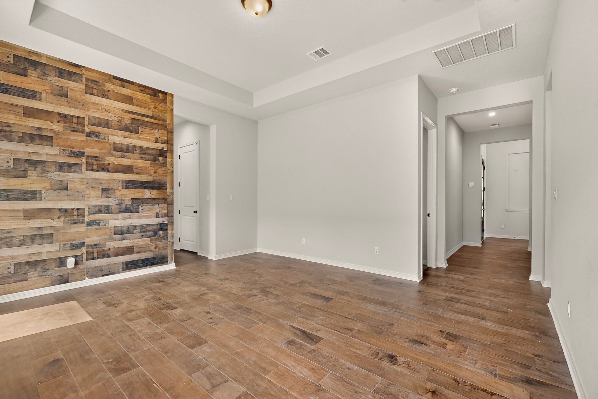 2433 La Mirada Street Leander, TX 78641 - Photo 18 of 25 A contemporary living area featuring a striking wood accent wall and durable wood-look tile flooring.