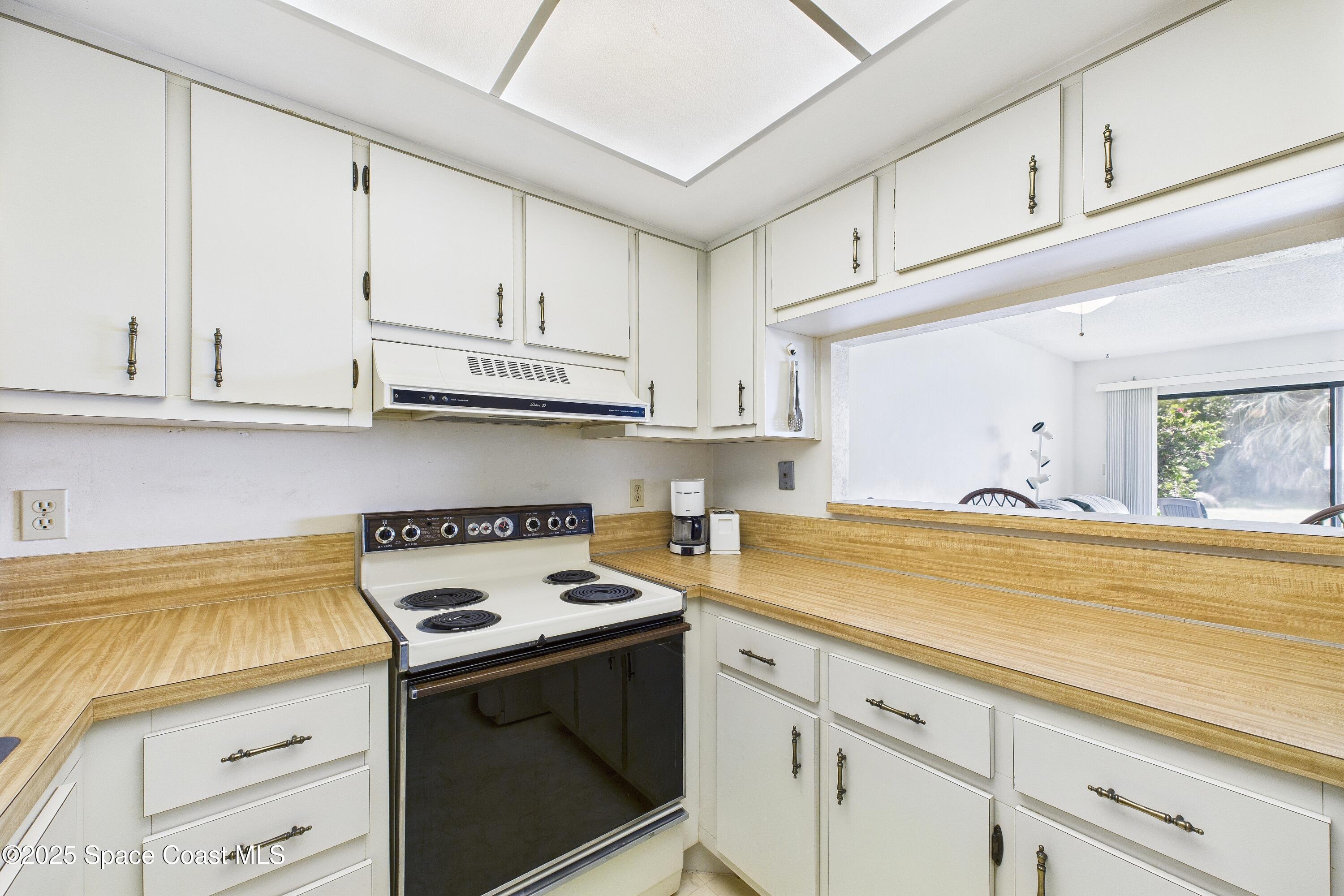 21 Cove Road, Unit 21E Melbourne Beach, FL 32951 - Photo 11 of 30 a kitchen with stainless steel appliances granite countertop a sink a stove and cabinets