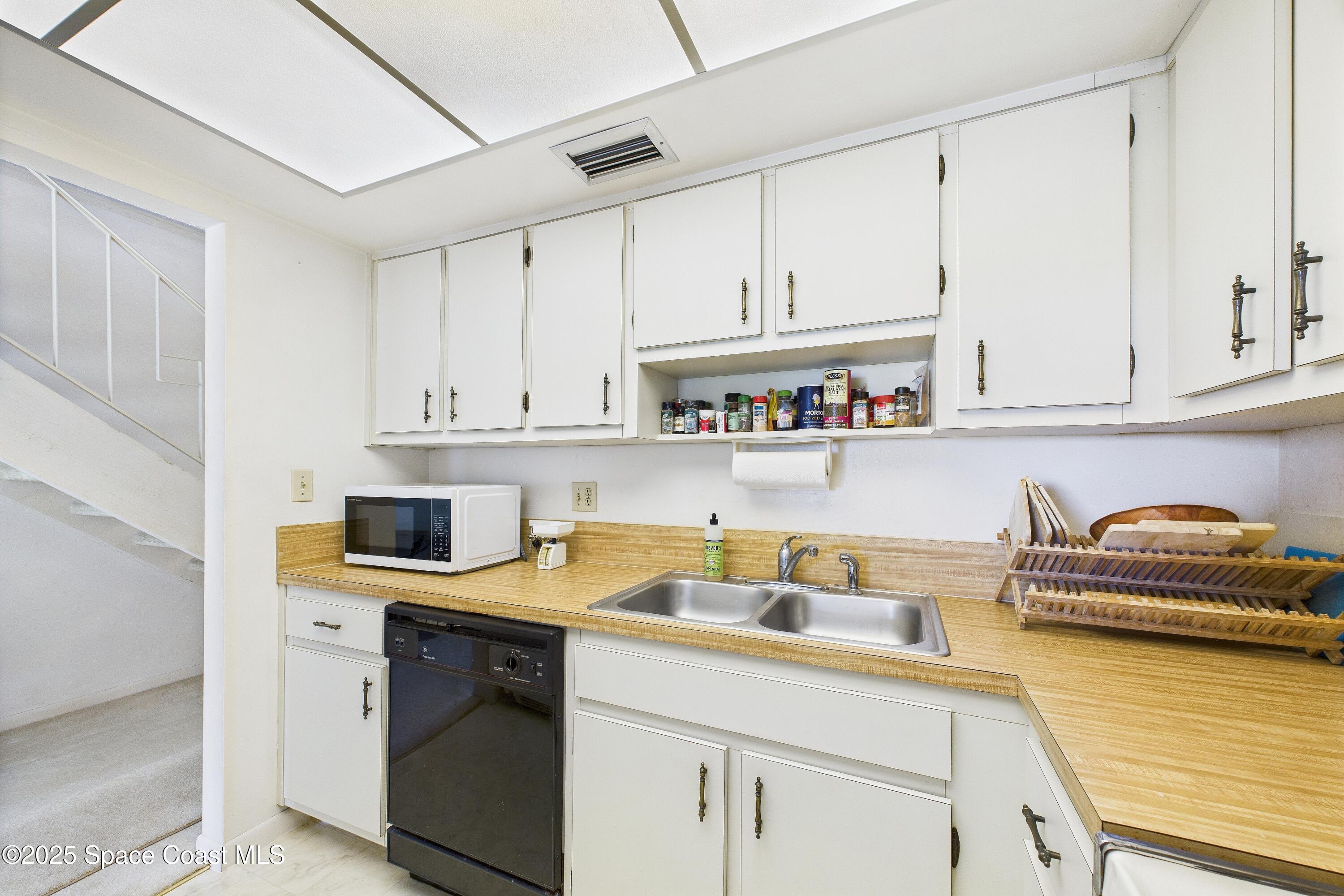 21 Cove Road, Unit 21E Melbourne Beach, FL 32951 - Photo 12 of 30 a kitchen with stainless steel appliances granite countertop a sink a stove and cabinets