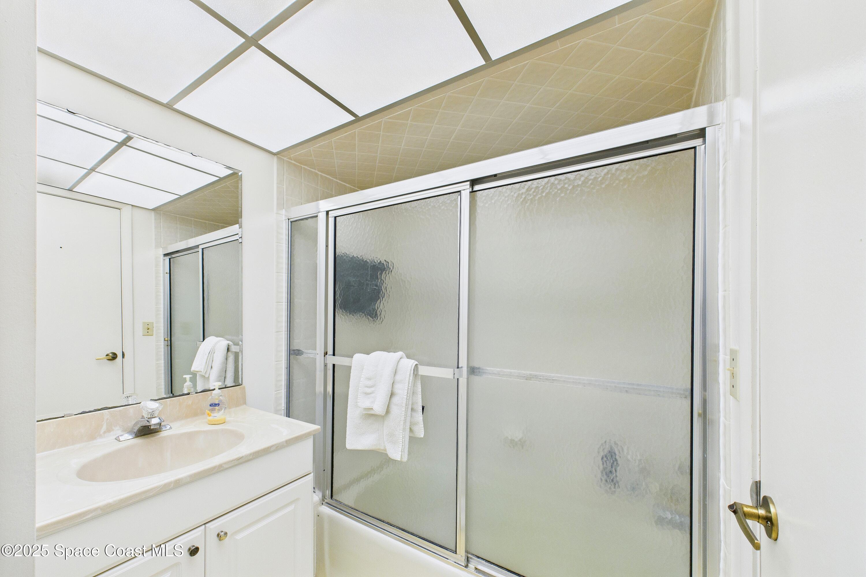 21 Cove Road, Unit 21E Melbourne Beach, FL 32951 - Photo 18 of 30 a bathroom with a shower sink and mirror