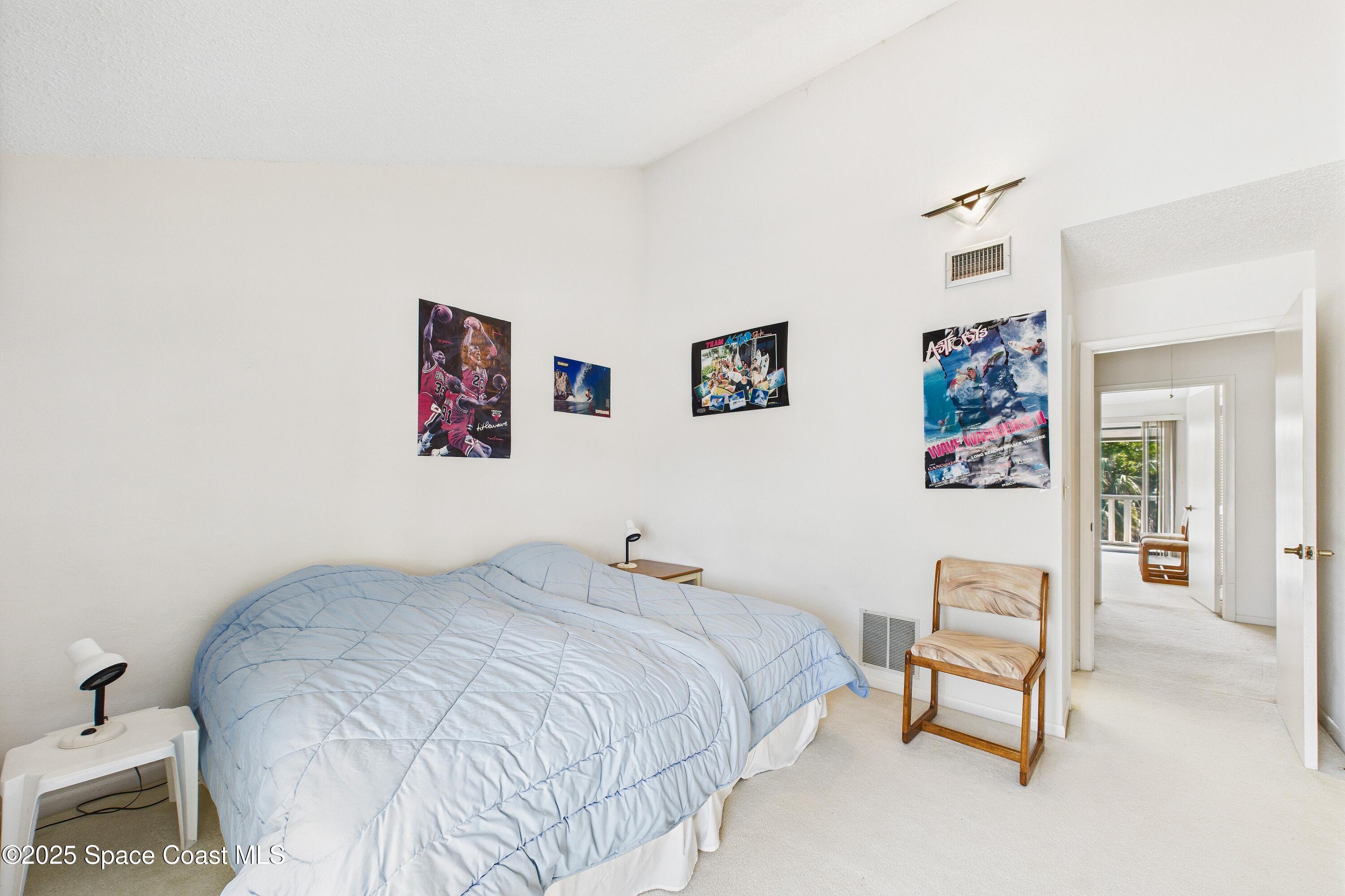 21 Cove Road, Unit 21E Melbourne Beach, FL 32951 - Photo 19 of 30 a bedroom with a bed and a chair