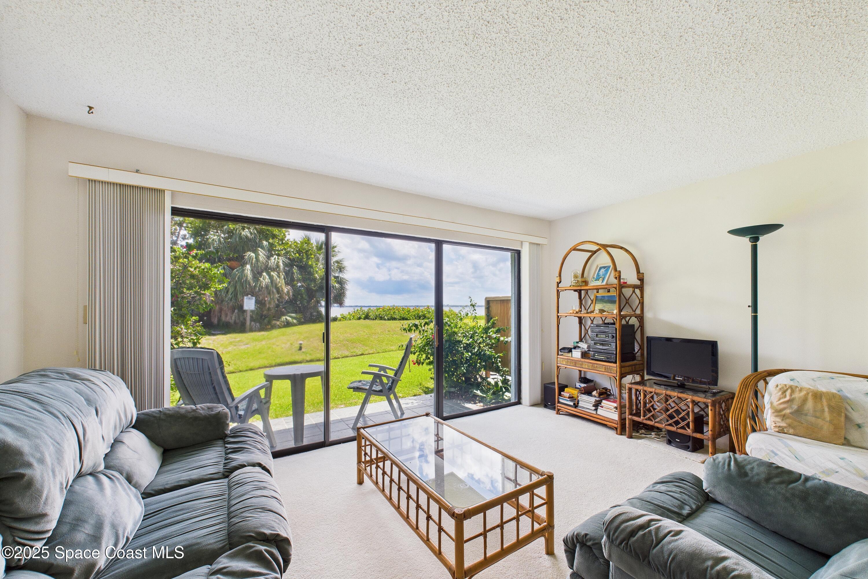 21 Cove Road, Unit 21E Melbourne Beach, FL 32951 - Photo 3 of 30 a living room with furniture and a large window