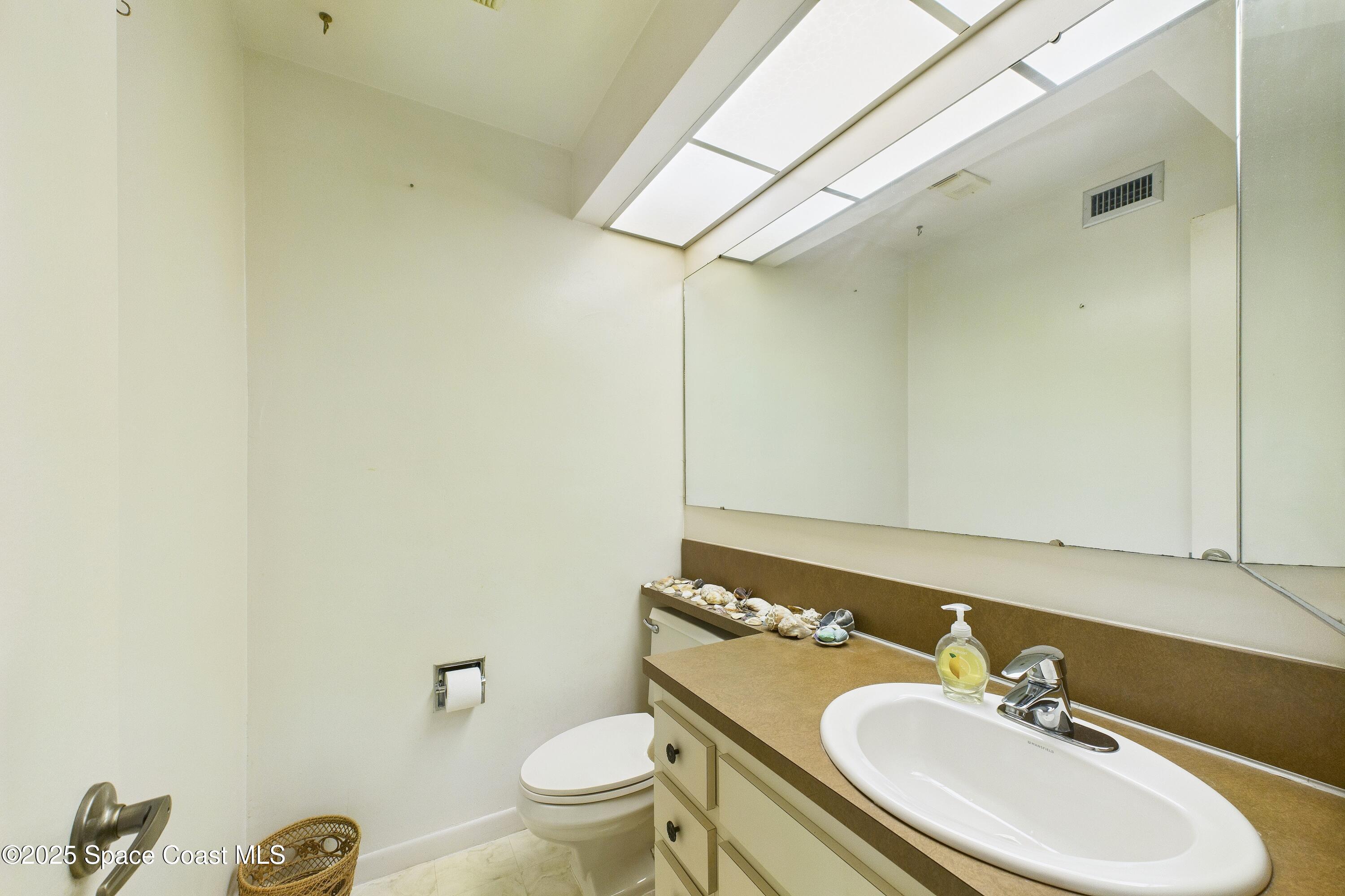 21 Cove Road, Unit 21E Melbourne Beach, FL 32951 - Photo 8 of 30 a bathroom with a sink toilet and mirror