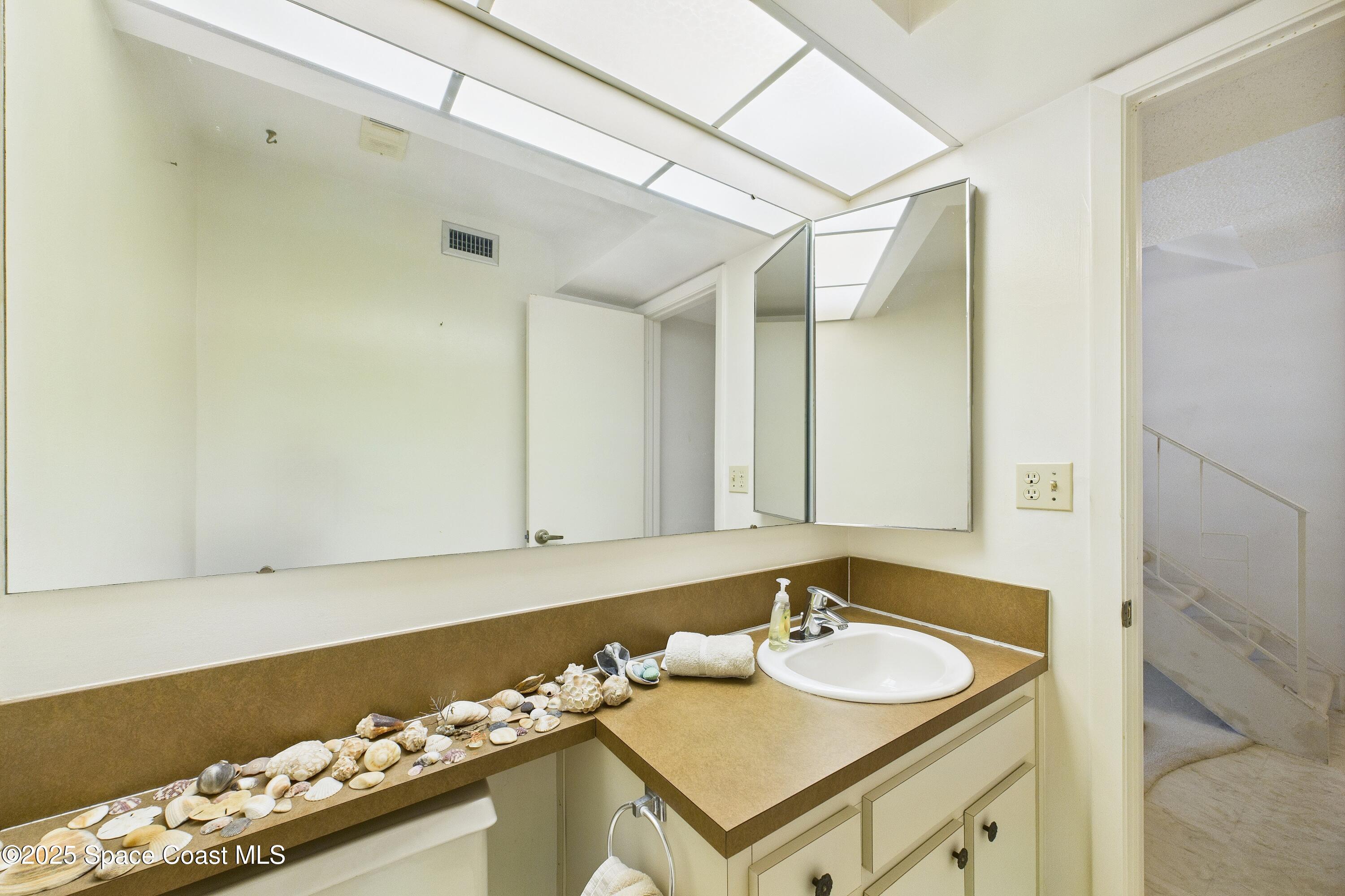 21 Cove Road, Unit 21E Melbourne Beach, FL 32951 - Photo 9 of 30 a bathroom with a sink vanity and a mirror