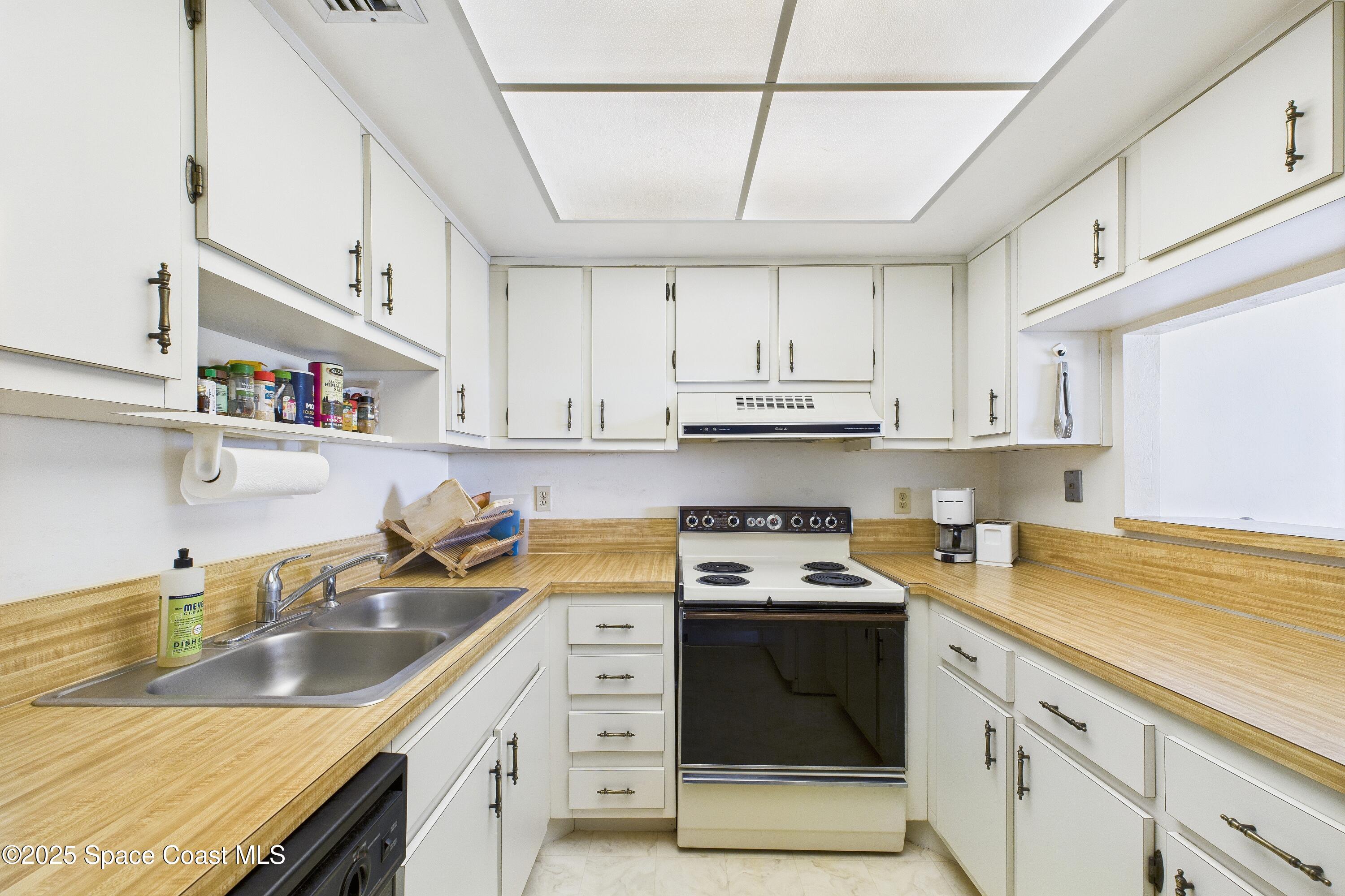 21 Cove Road, Unit 21E Melbourne Beach, FL 32951 - Photo 10 of 30 a kitchen with stainless steel appliances granite countertop a sink stove and cabinets