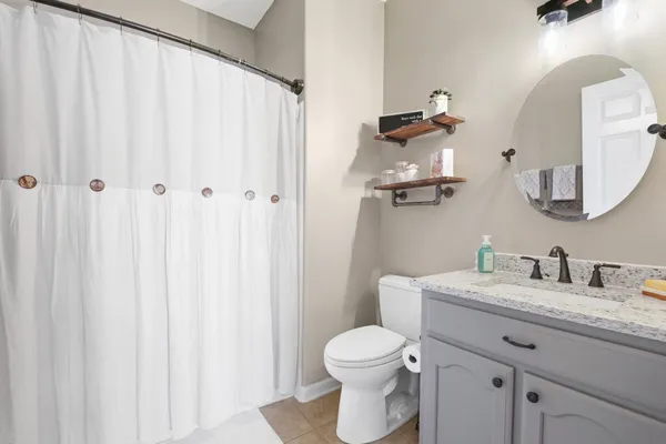 a bathroom with a granite countertop sink vanity mirror and toilet