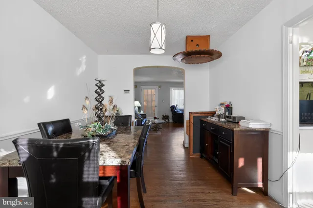 a kitchen with stainless steel appliances granite countertop a stove top oven a dining table and chairs with wooden floor