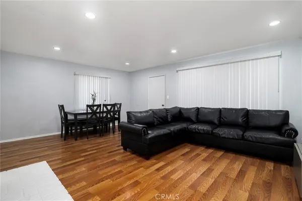 a living room with furniture and a dining table with wooden floor
