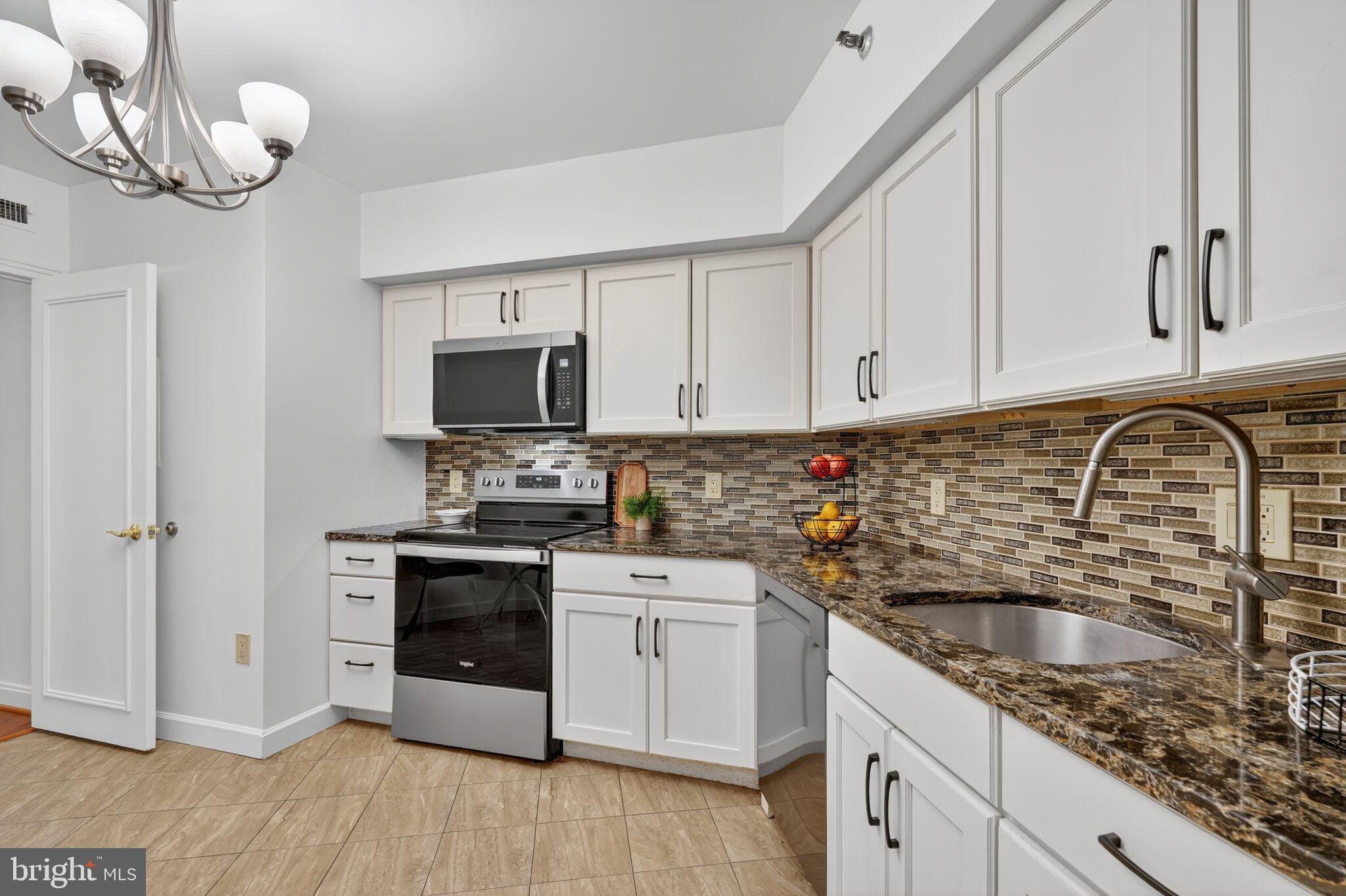 4550 North Park Avenue, Unit 814 Chevy Chase, MD 20815 - Photo 10 of 25 a kitchen with granite countertop a sink stainless steel appliances and white cabinets